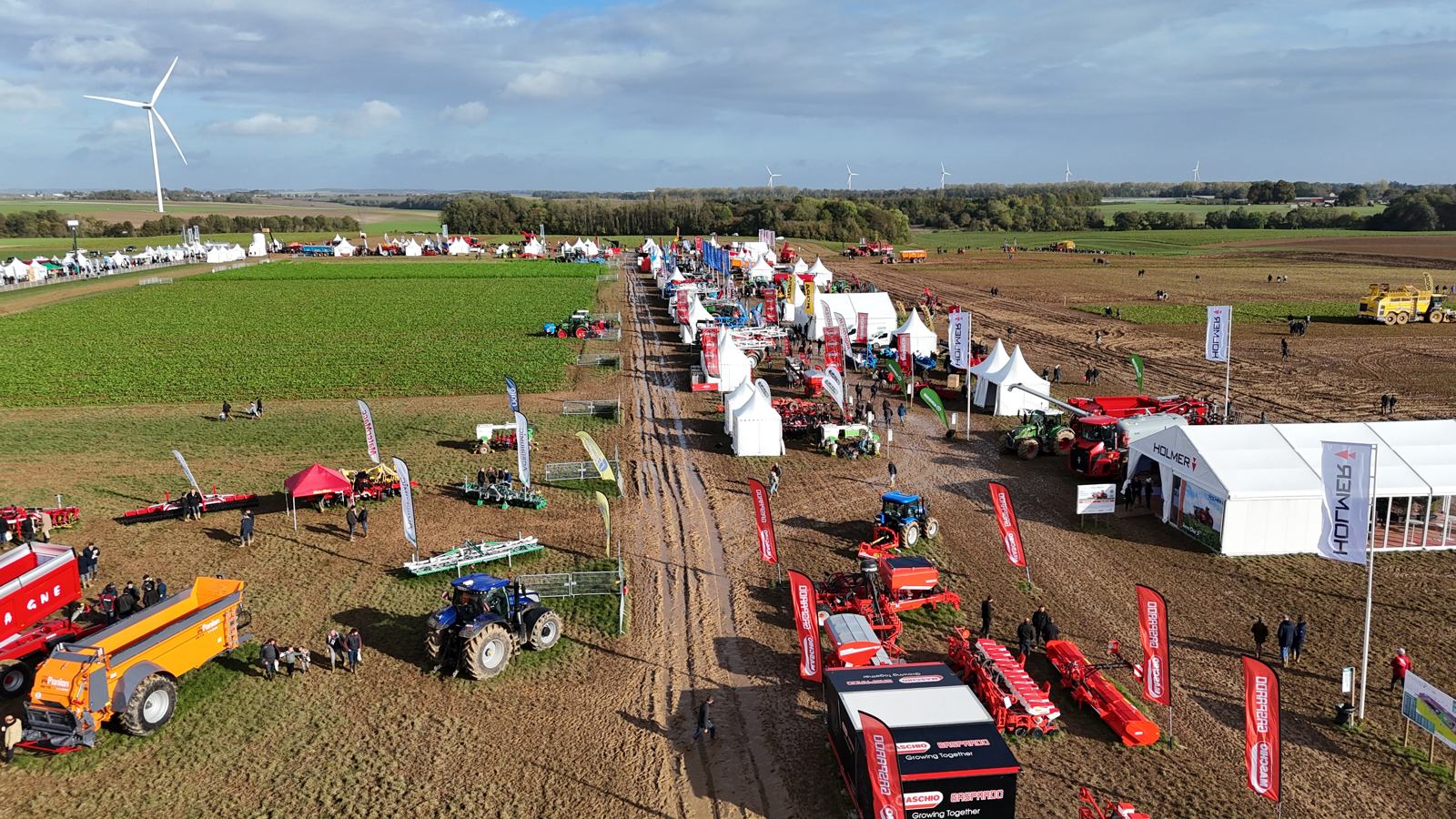 Vue aérienne d'un salon agricole en plein champ, stands, tentes et engins